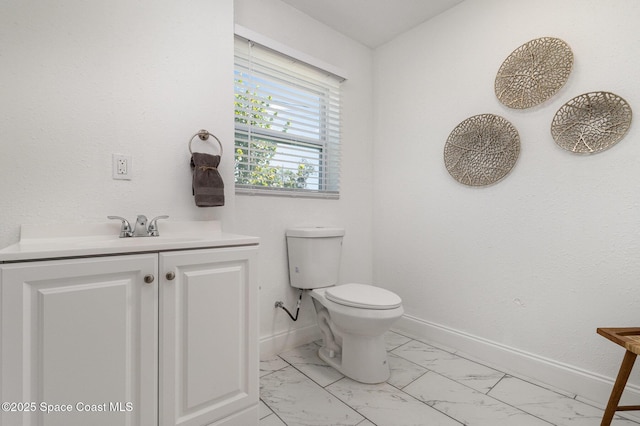 half bathroom with vanity, toilet, baseboards, and marble finish floor