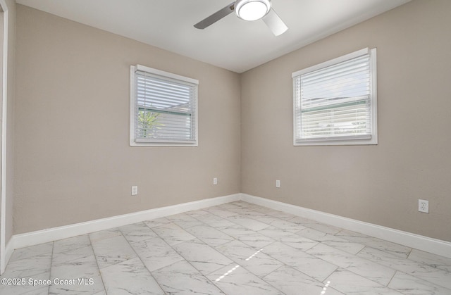 unfurnished room featuring a wealth of natural light, marble finish floor, and baseboards