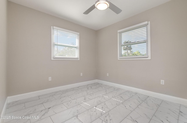 empty room featuring baseboards, marble finish floor, and a ceiling fan