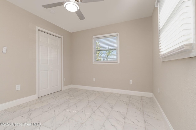 unfurnished bedroom with baseboards, marble finish floor, and a ceiling fan