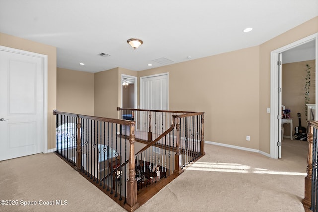 hall featuring light carpet, an upstairs landing, visible vents, and baseboards