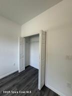 unfurnished bedroom with dark wood-type flooring and a closet