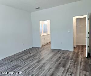 unfurnished bedroom featuring dark hardwood / wood-style flooring and connected bathroom