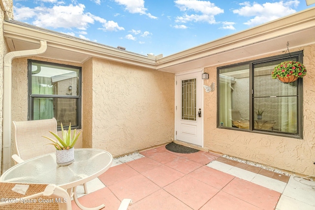 view of exterior entry featuring a patio area and stucco siding