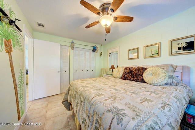 bedroom with light tile patterned flooring, ceiling fan, and two closets