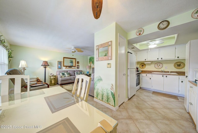 kitchen with sink, ceiling fan, white cabinetry, light tile patterned flooring, and white fridge