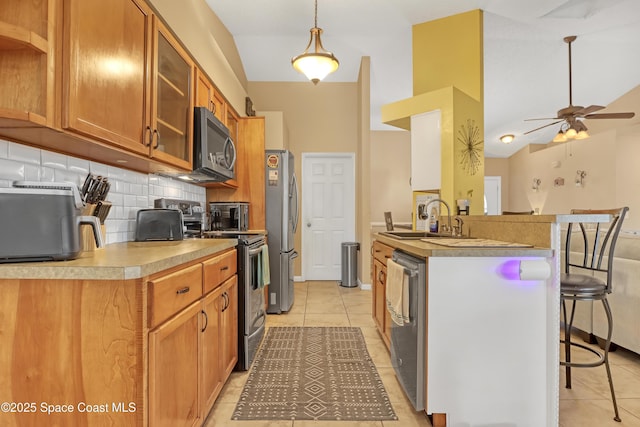 kitchen with sink, stainless steel appliances, decorative backsplash, a kitchen bar, and decorative light fixtures