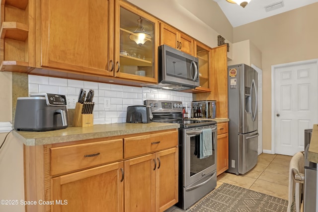 kitchen with stainless steel appliances, light tile patterned floors, and backsplash