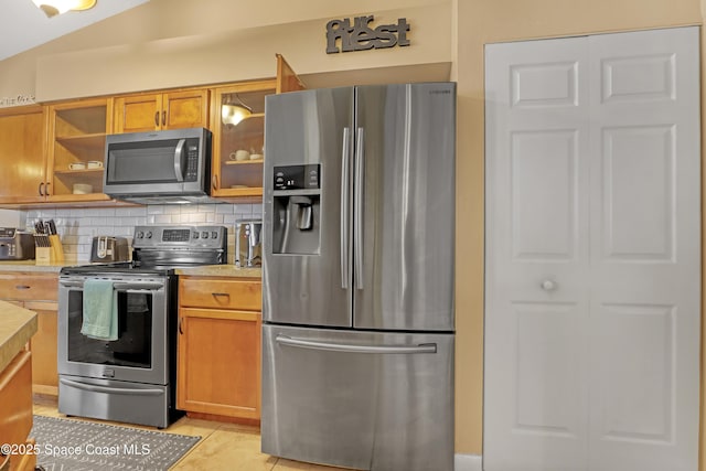 kitchen with tasteful backsplash, appliances with stainless steel finishes, and light tile patterned flooring