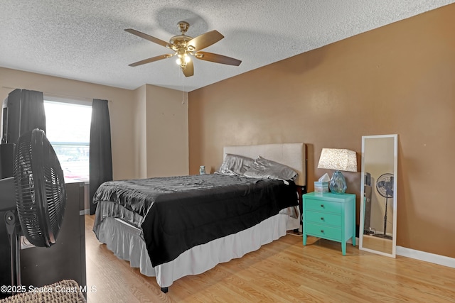 bedroom featuring ceiling fan, wood-type flooring, and a textured ceiling