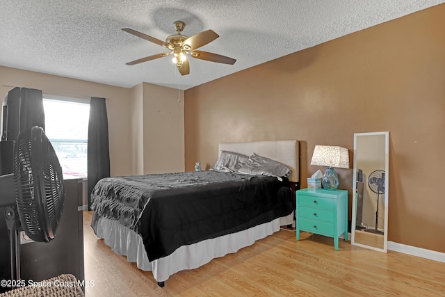 bedroom featuring ceiling fan, light hardwood / wood-style floors, and a textured ceiling