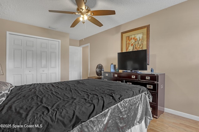 bedroom with ceiling fan, light hardwood / wood-style floors, a closet, and a textured ceiling