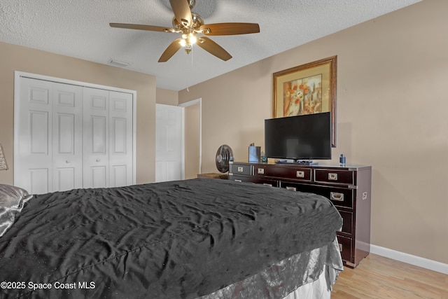 bedroom featuring ceiling fan, light hardwood / wood-style floors, a closet, and a textured ceiling