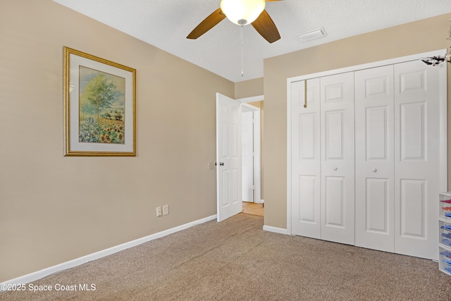 unfurnished bedroom with light carpet, a textured ceiling, ceiling fan, and a closet