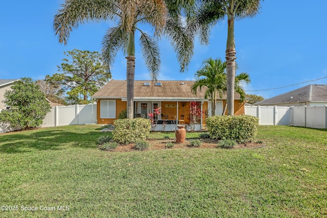 rear view of property featuring a sunroom and a lawn