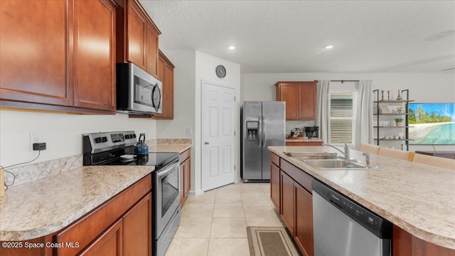 kitchen featuring sink, a kitchen island with sink, stainless steel appliances, a textured ceiling, and light tile patterned flooring