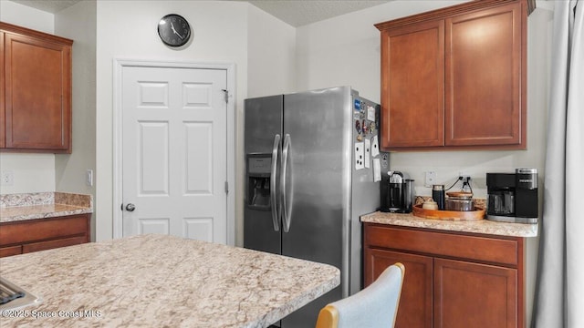 kitchen with stainless steel refrigerator with ice dispenser and a textured ceiling