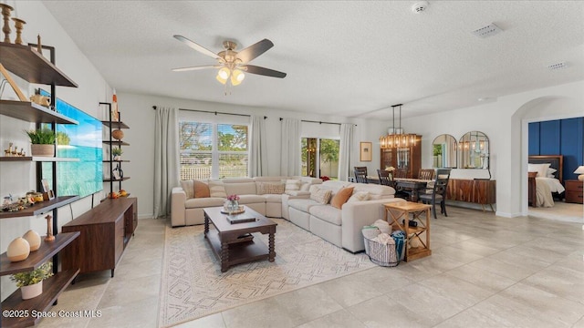 tiled living room with ceiling fan with notable chandelier and a textured ceiling