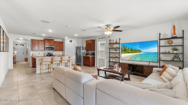 living room featuring light tile patterned flooring, ceiling fan, and a textured ceiling