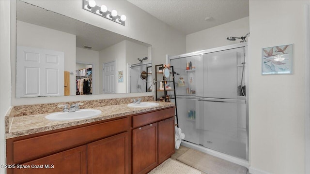 bathroom with walk in shower, vanity, and a textured ceiling