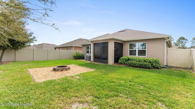 rear view of property with a sunroom, a fire pit, and a lawn