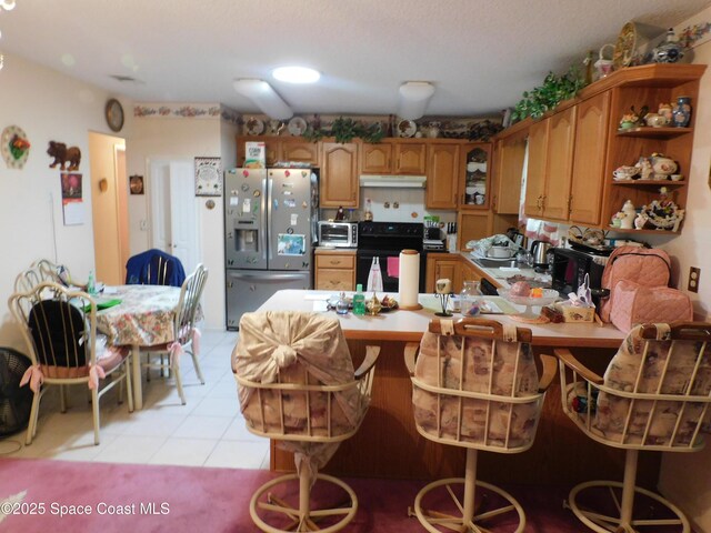 kitchen featuring light tile patterned flooring, black electric range oven, kitchen peninsula, and stainless steel fridge with ice dispenser