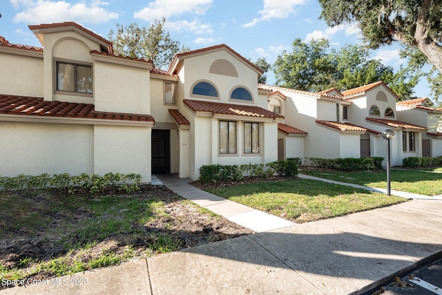 mediterranean / spanish home with a front lawn