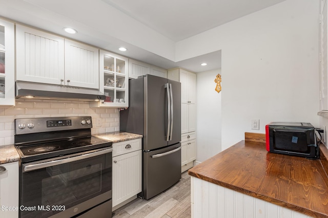 kitchen with stainless steel appliances, butcher block counters, light hardwood / wood-style floors, tasteful backsplash, and white cabinets