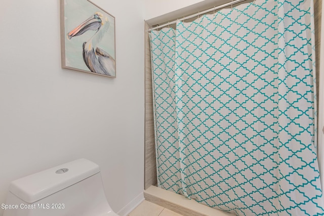 bathroom featuring tile patterned floors, toilet, and a shower with curtain