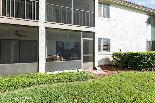 back of property with a sunroom, a lawn, and ceiling fan