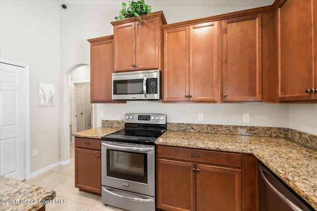 kitchen with light stone counters, appliances with stainless steel finishes, and light tile patterned flooring