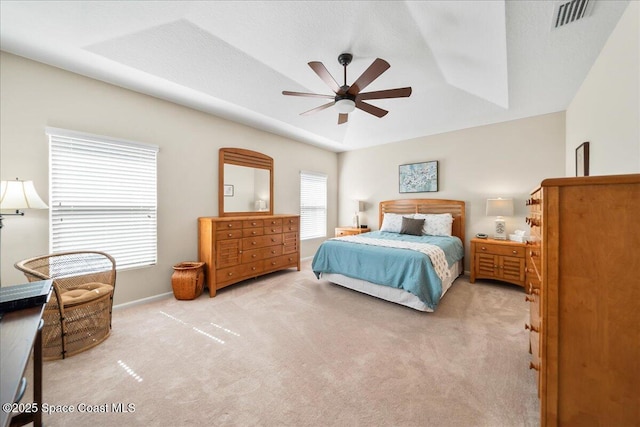 carpeted bedroom featuring ceiling fan and a tray ceiling