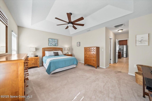 carpeted bedroom featuring a raised ceiling, stainless steel fridge, and ceiling fan