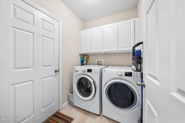 washroom featuring cabinets, light tile patterned floors, washing machine and clothes dryer, and a textured ceiling