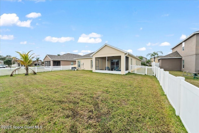 back of property featuring a sunroom and a lawn