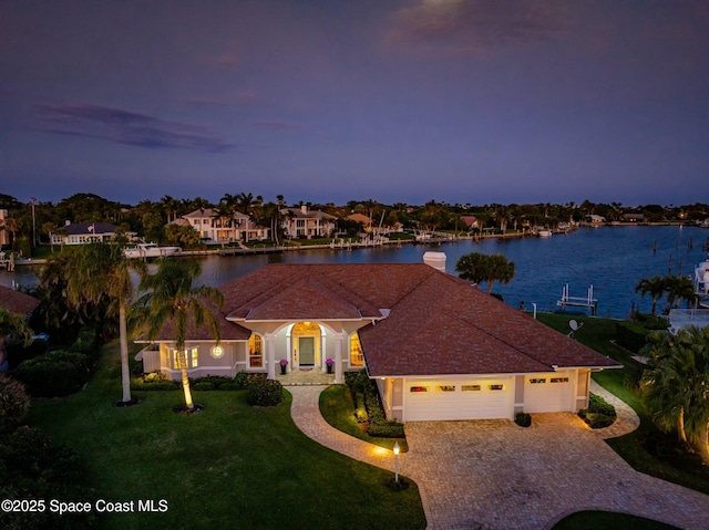 mediterranean / spanish house with a water view, a garage, and a yard