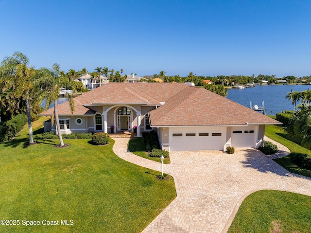 ranch-style house with a garage, a front yard, and a water view