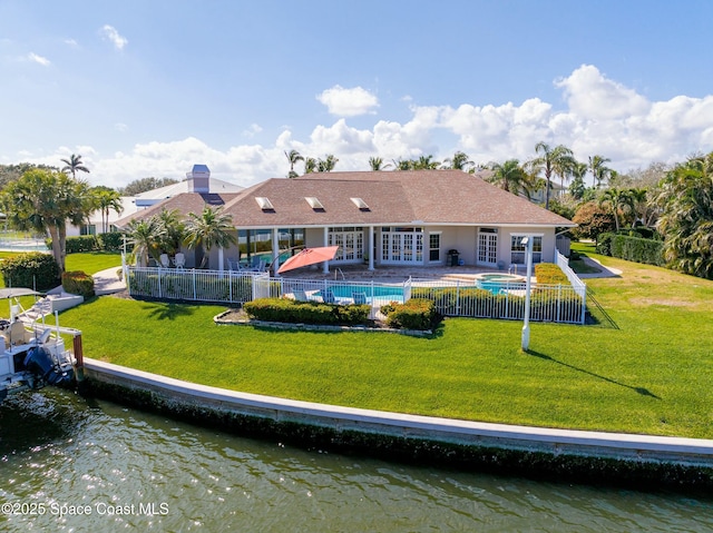 rear view of house with a water view, a yard, and a fenced in pool