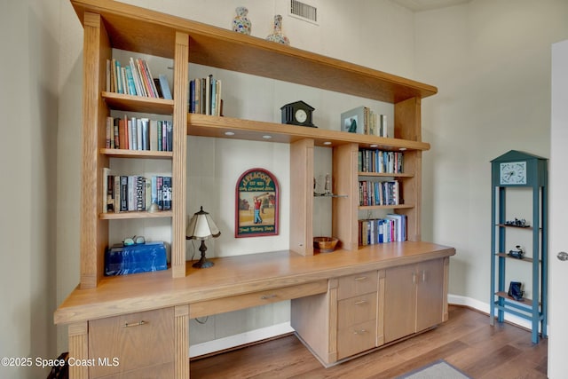 office space featuring built in desk and light hardwood / wood-style flooring