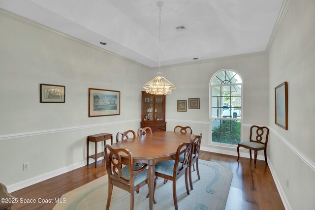 dining space featuring ornamental molding, dark hardwood / wood-style flooring, and a tray ceiling