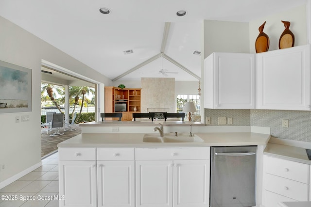 kitchen featuring sink, lofted ceiling with beams, light tile patterned floors, stainless steel dishwasher, and ceiling fan