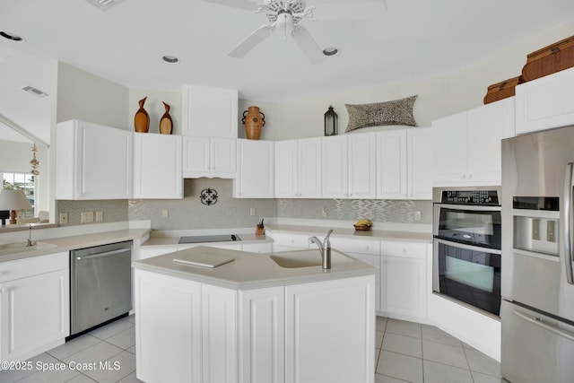 kitchen with sink, light tile patterned flooring, stainless steel appliances, and a center island with sink