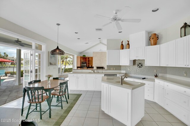 kitchen featuring vaulted ceiling, decorative light fixtures, decorative backsplash, light tile patterned floors, and kitchen peninsula