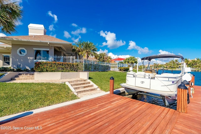 view of dock with a water view and a lawn