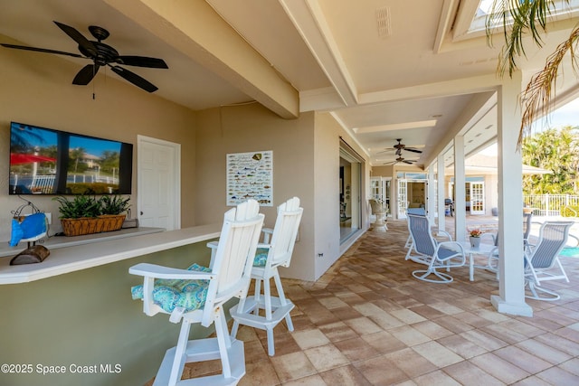 view of patio featuring ceiling fan and exterior bar