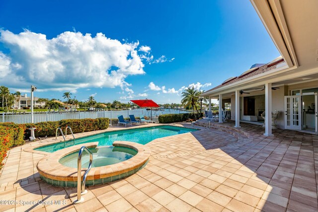 view of swimming pool with french doors, an in ground hot tub, a water view, and a patio area