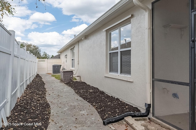 view of property exterior featuring central air condition unit, a fenced backyard, and stucco siding