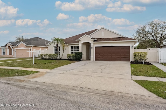 ranch-style house with fence, driveway, a gate, stucco siding, and a front lawn