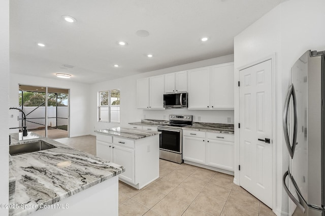 kitchen featuring appliances with stainless steel finishes, a sink, white cabinetry, and a center island