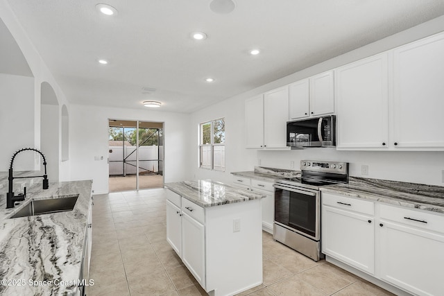 kitchen featuring a kitchen island, stainless steel appliances, a sink, and light tile patterned flooring